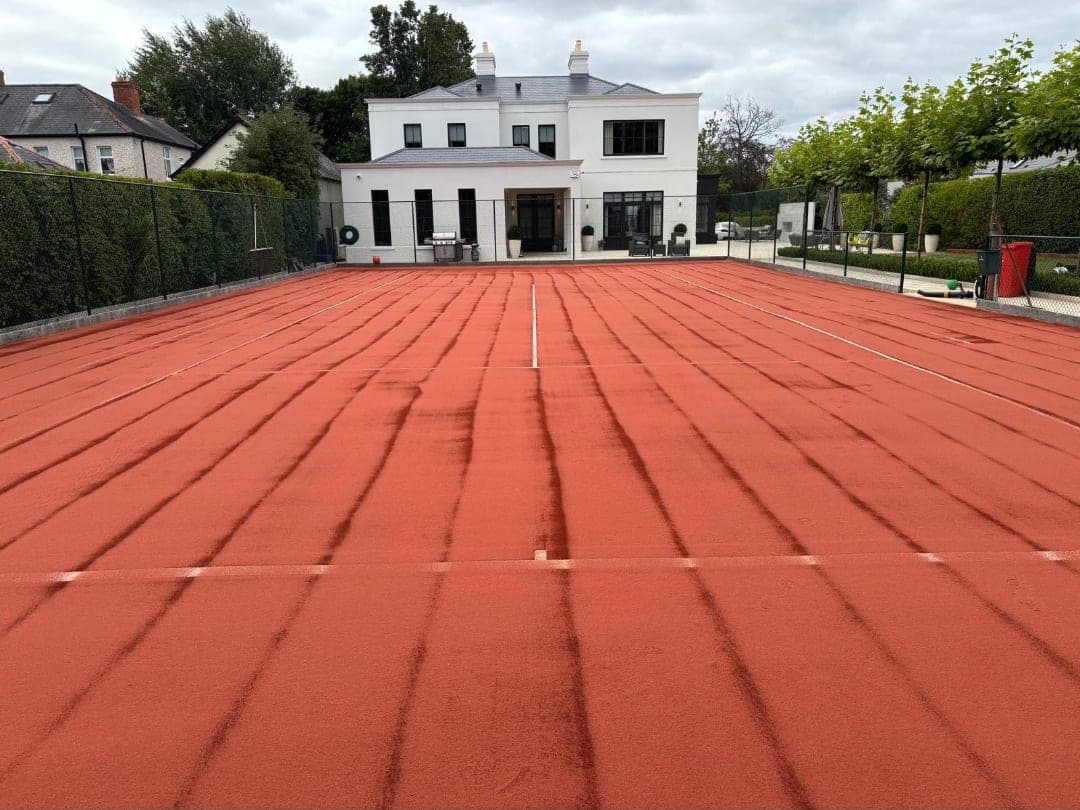 Artificial clay tennis court before rejuvenation, showing compacted silt lines across the playing surface